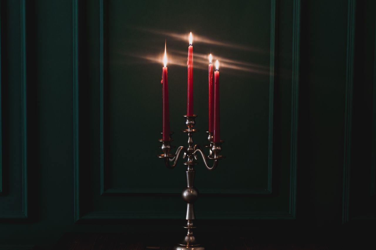 Elegant red candles on a silver candelabra set in a dark room, creating a warm ambiance.