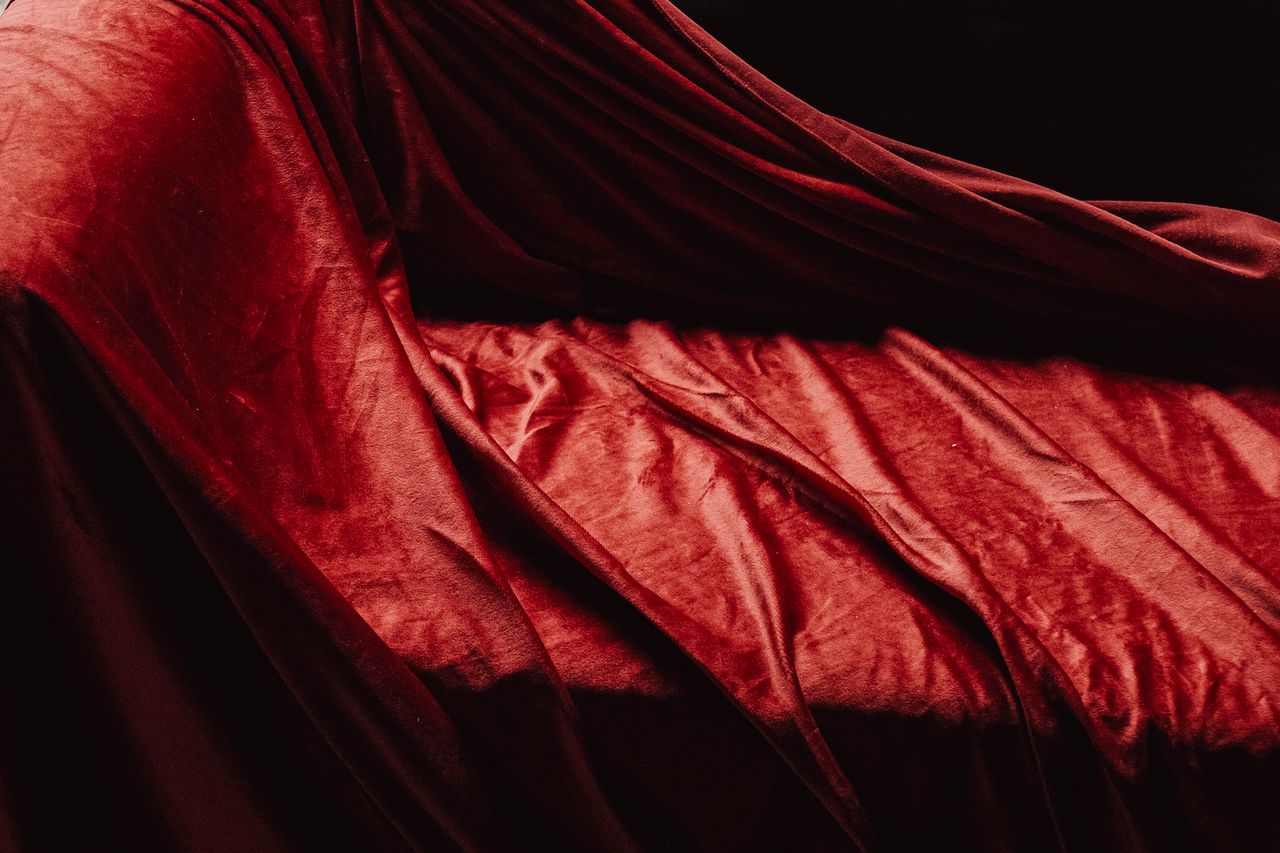 Rich texture of luxurious red velvet fabric draped elegantly creating soft shadows and highlights.